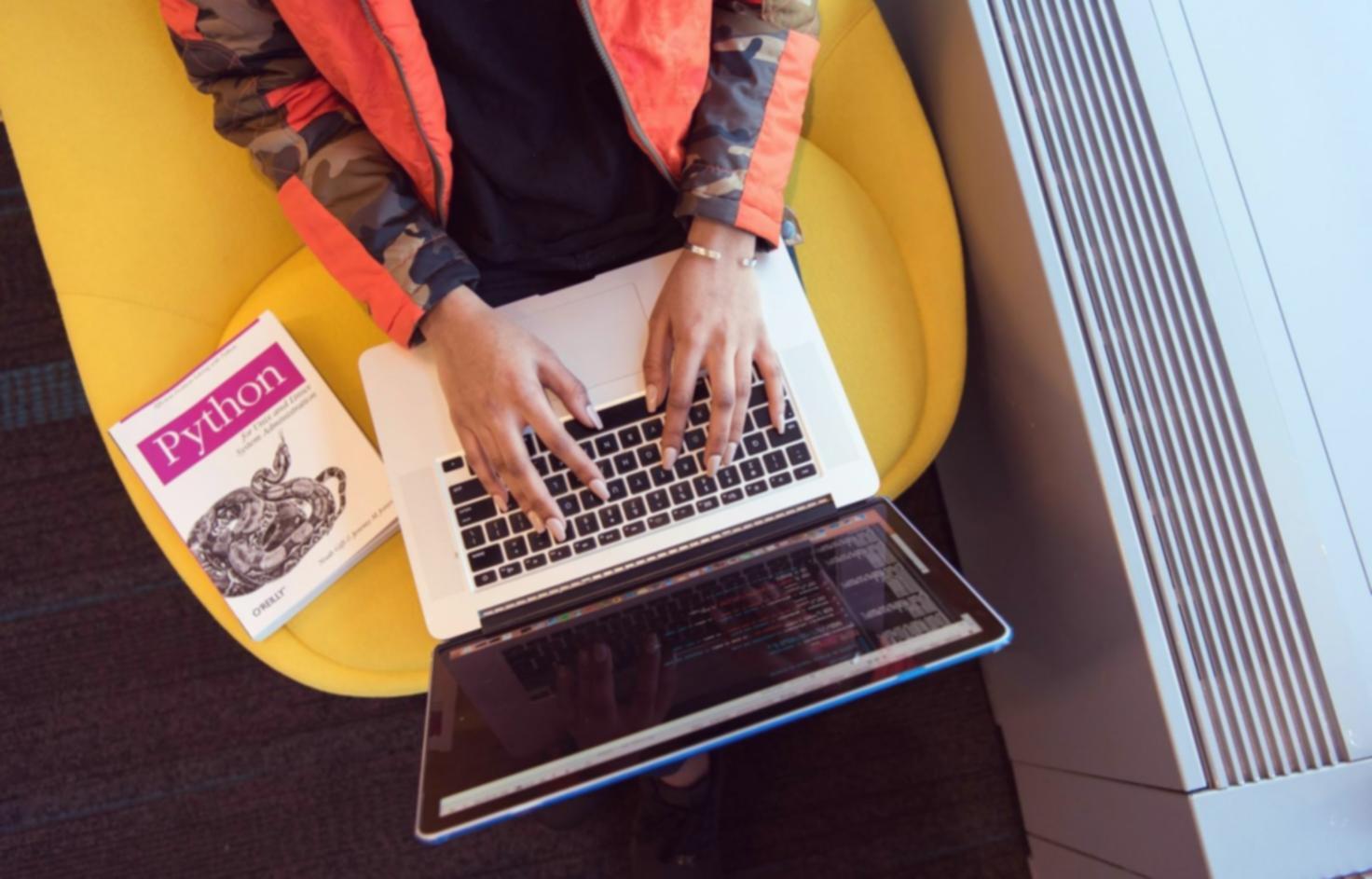 Nahaufnahme von Händen beim Programmieren eines Mobile Games auf dem Laptop